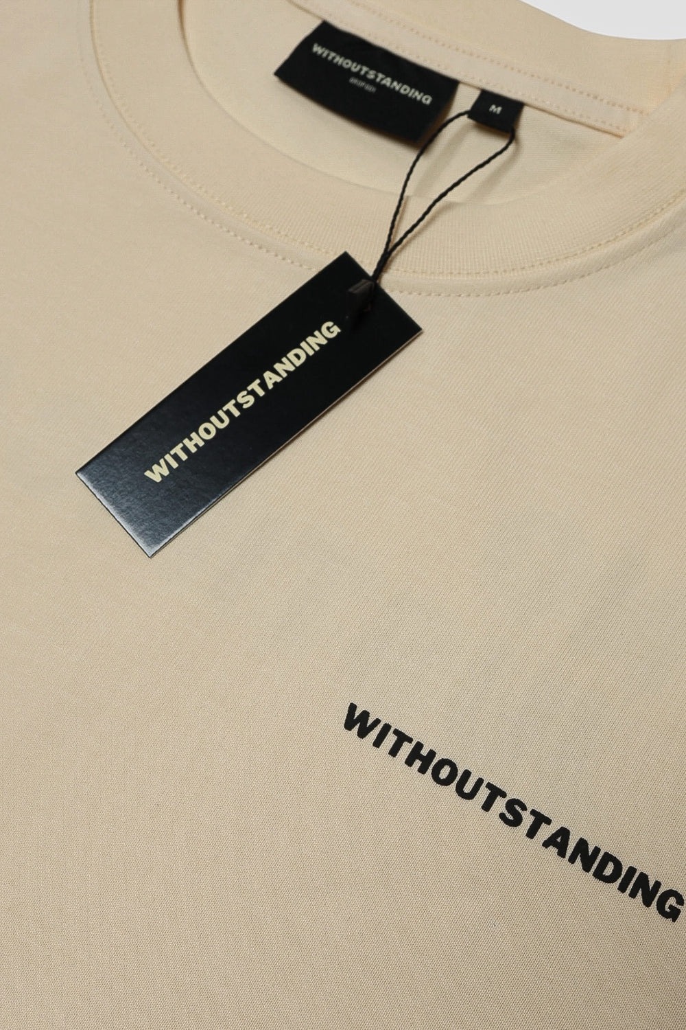Black WITHOUTSTANDING hang tag on the seedpearl DROP 001 tee