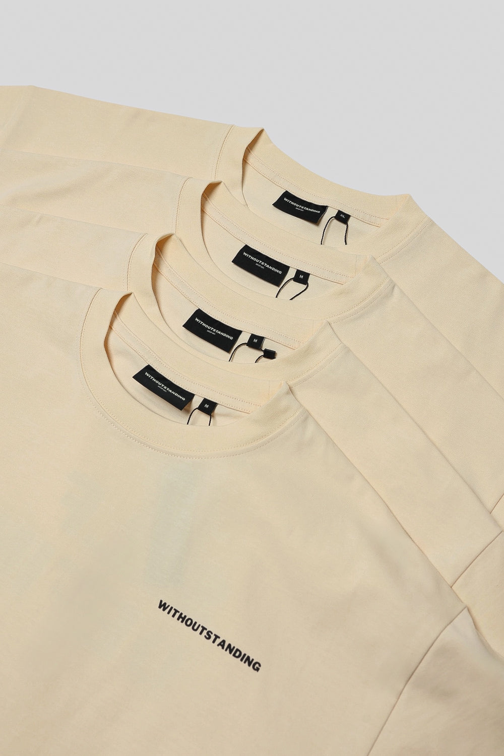Stacked collars of seedpearl DROP 001 tees with WITHOUTSTANDING labels