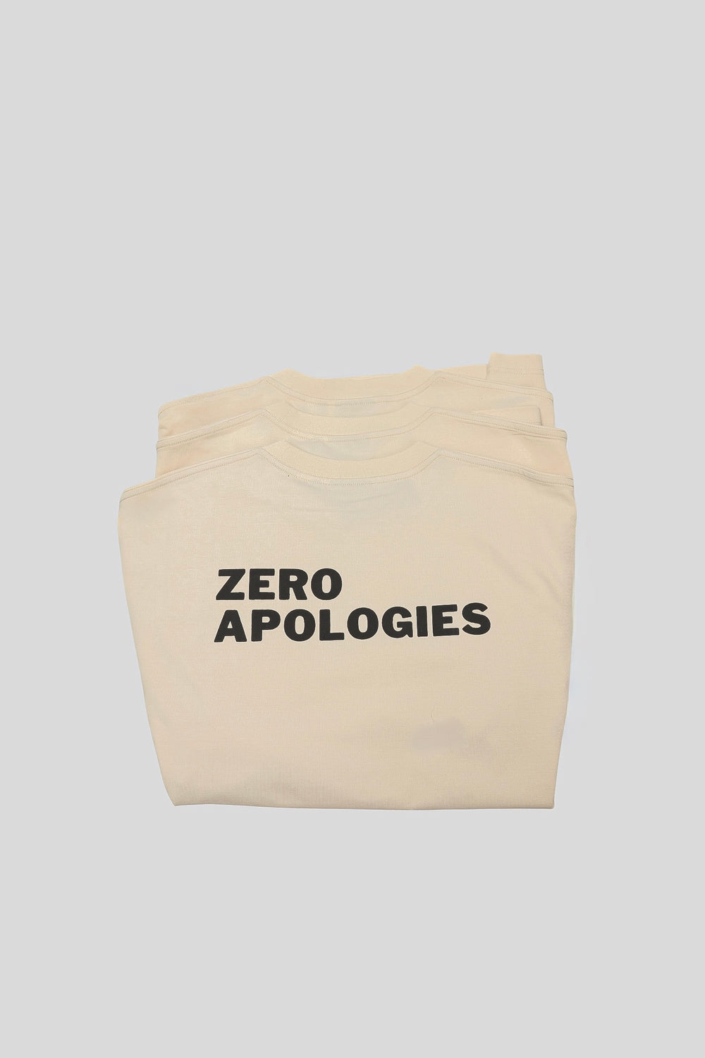 Folded seedpearl DROP 001 tee with the ZERO APOLOGIES print visible
