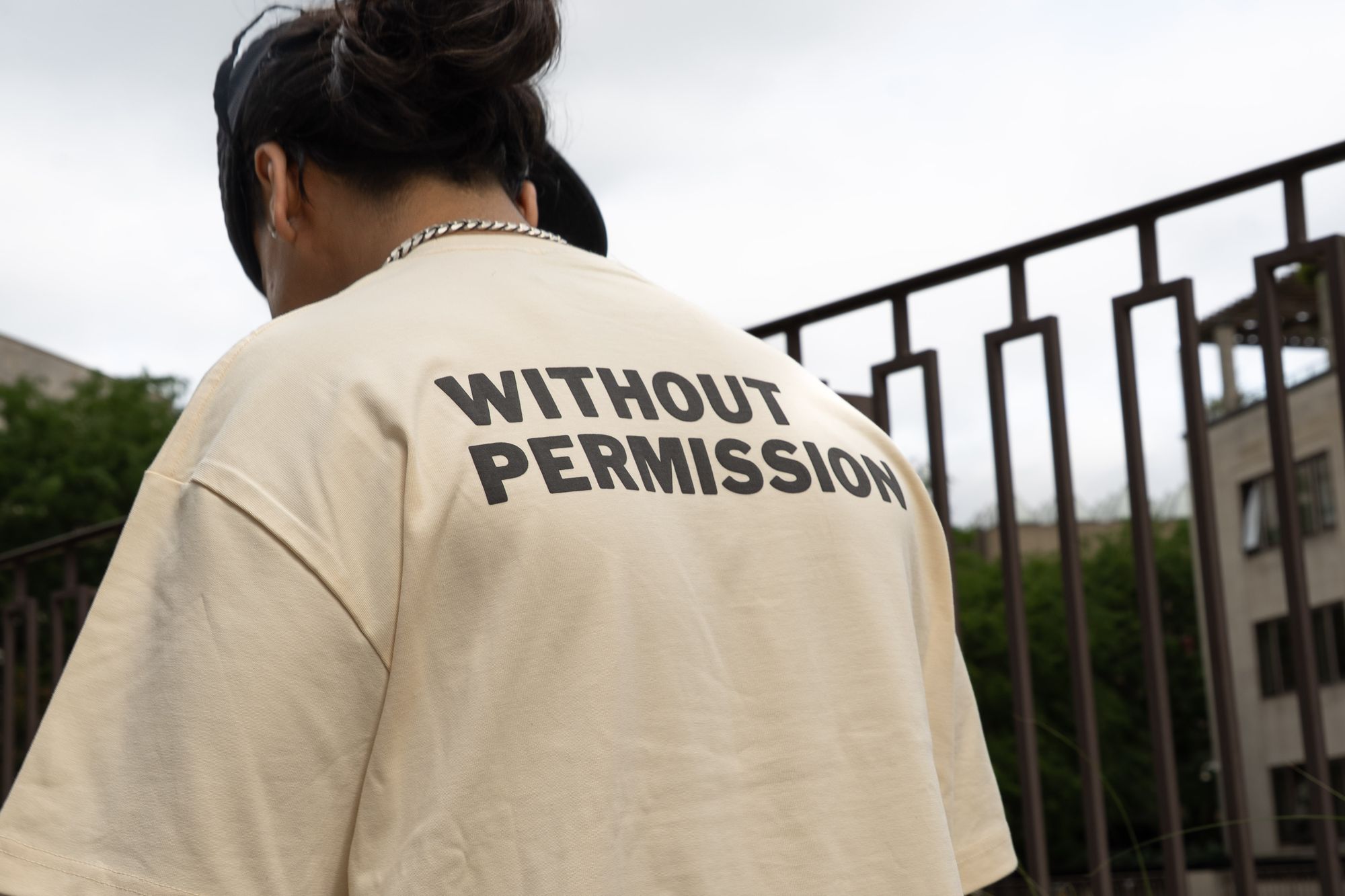 WITHOUT PERMISSION raised print across the back of the tee, worn outdoors