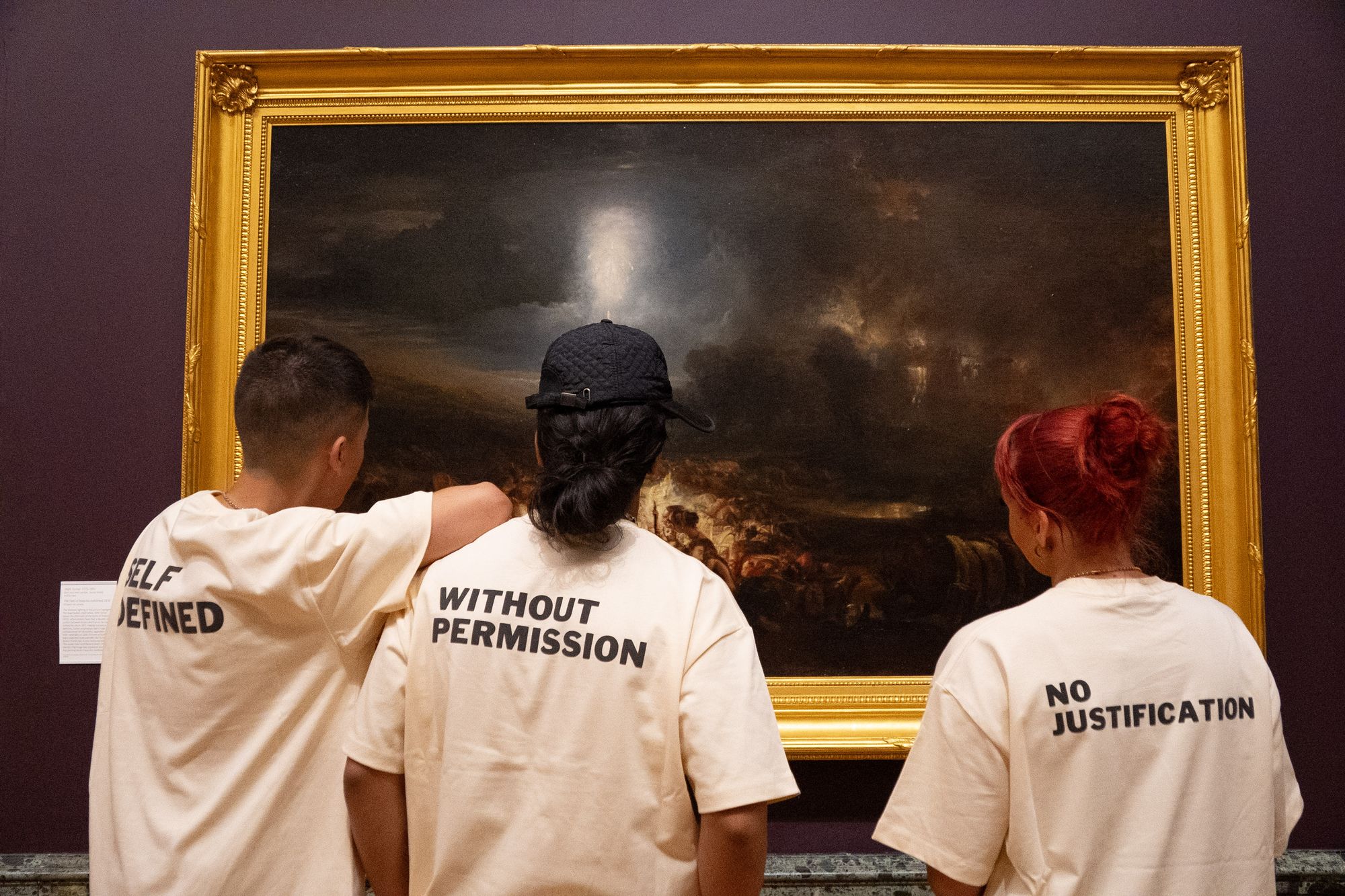 Two models in DROP 001 tees looking at paintings in a gallery